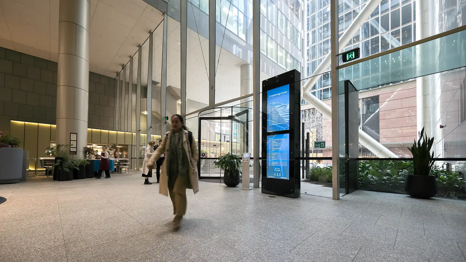 Vertical Multi-Screen Digital Tenant Directory in large glass filled commercial building foyer at 9 Castlereagh Street Sydney. Image shows office workers passing by the tall Tenant Directory