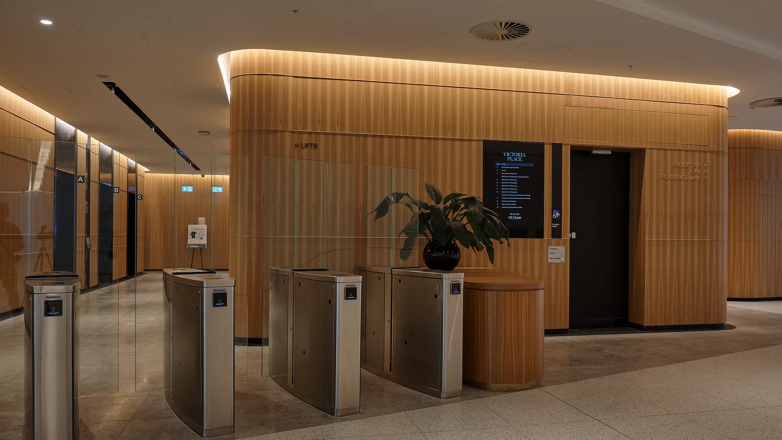 Streamline Series Surface mounted Digital Tenant Directory in the modern foyer of 200 Victoria Parade. Image shows Digital Directory mounted on wood panelled wall adjacent to the security gates to the lift lobby.